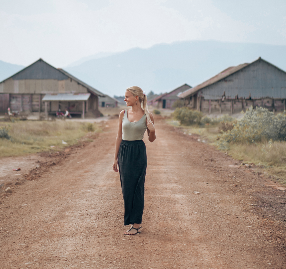 smiling_woman_standing_on_dirt_road_in_village-scopio